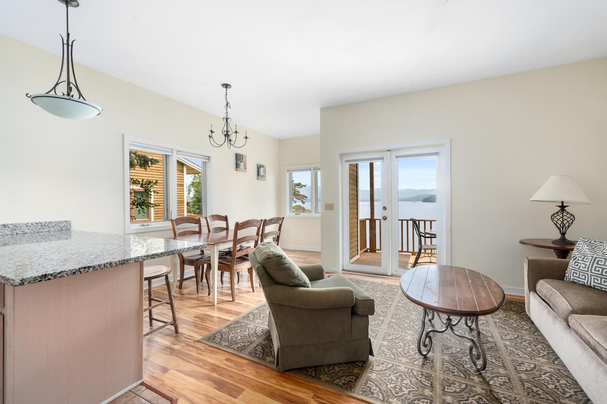 A spacious living area with a kitchen, dining area, and a view of the outdoors.