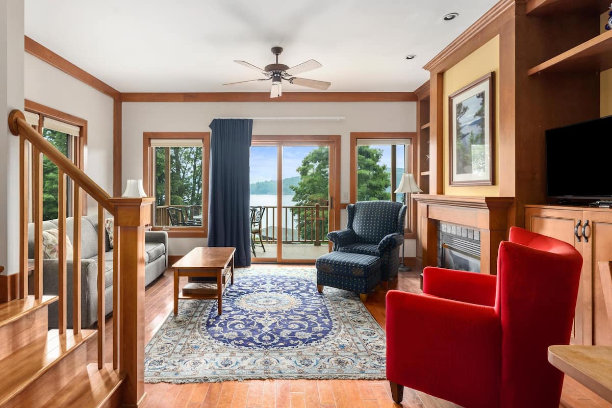 A spacious living room with a large window, a fireplace, and a television.