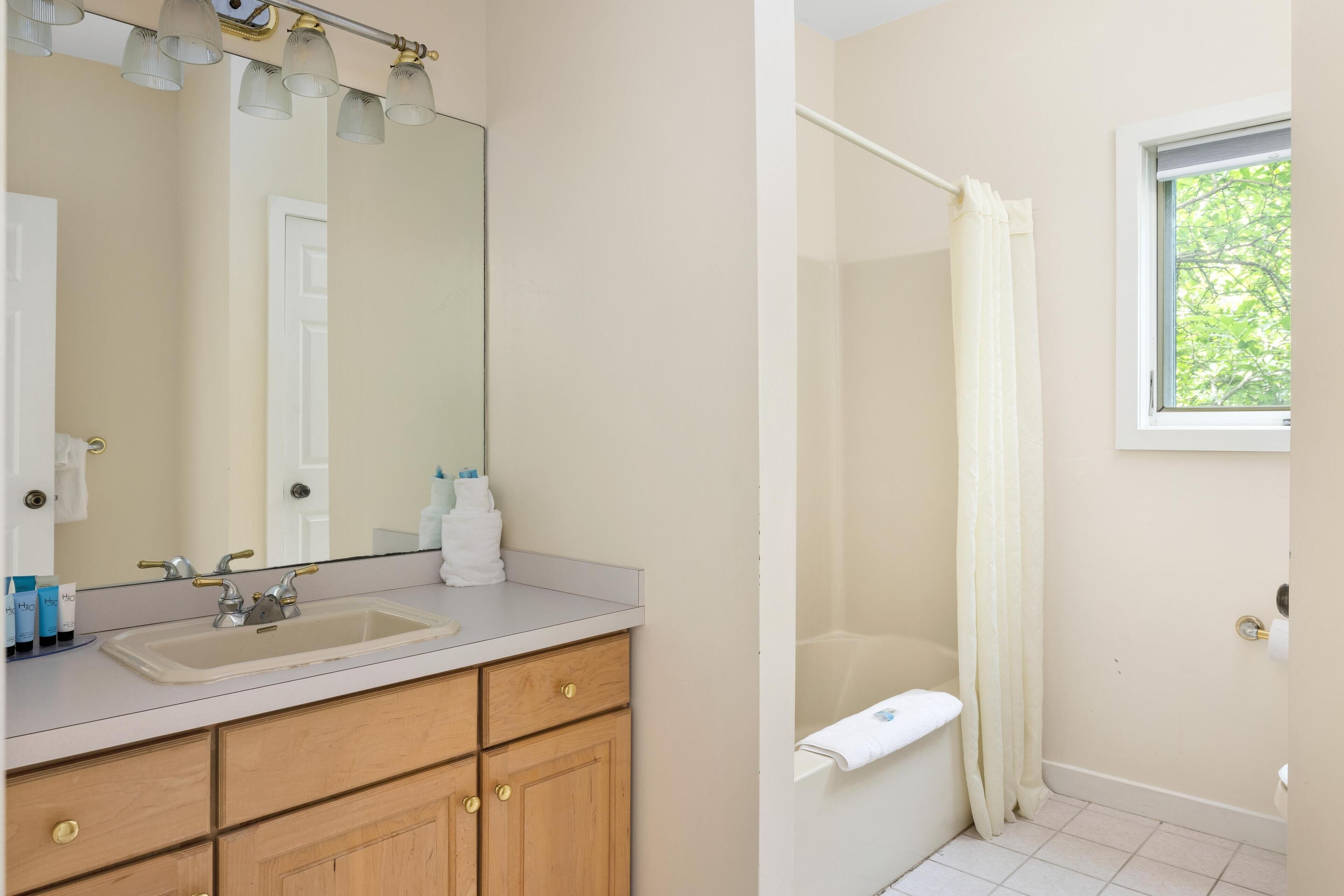A bathroom with a sink, mirror, and shower curtain.