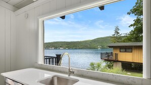 Una cucina con una grande finestra che si affaccia su un lago e un edificio in legno.