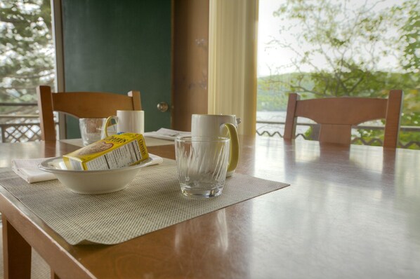 A dining table with a bowl of cereal, a glass of water, and a mug. - Sun Castle Resort (Lake George)