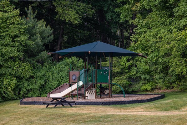 A playground with a slide, climbing structure, and a covered seating area. - Sun Castle Resort (Lake George)