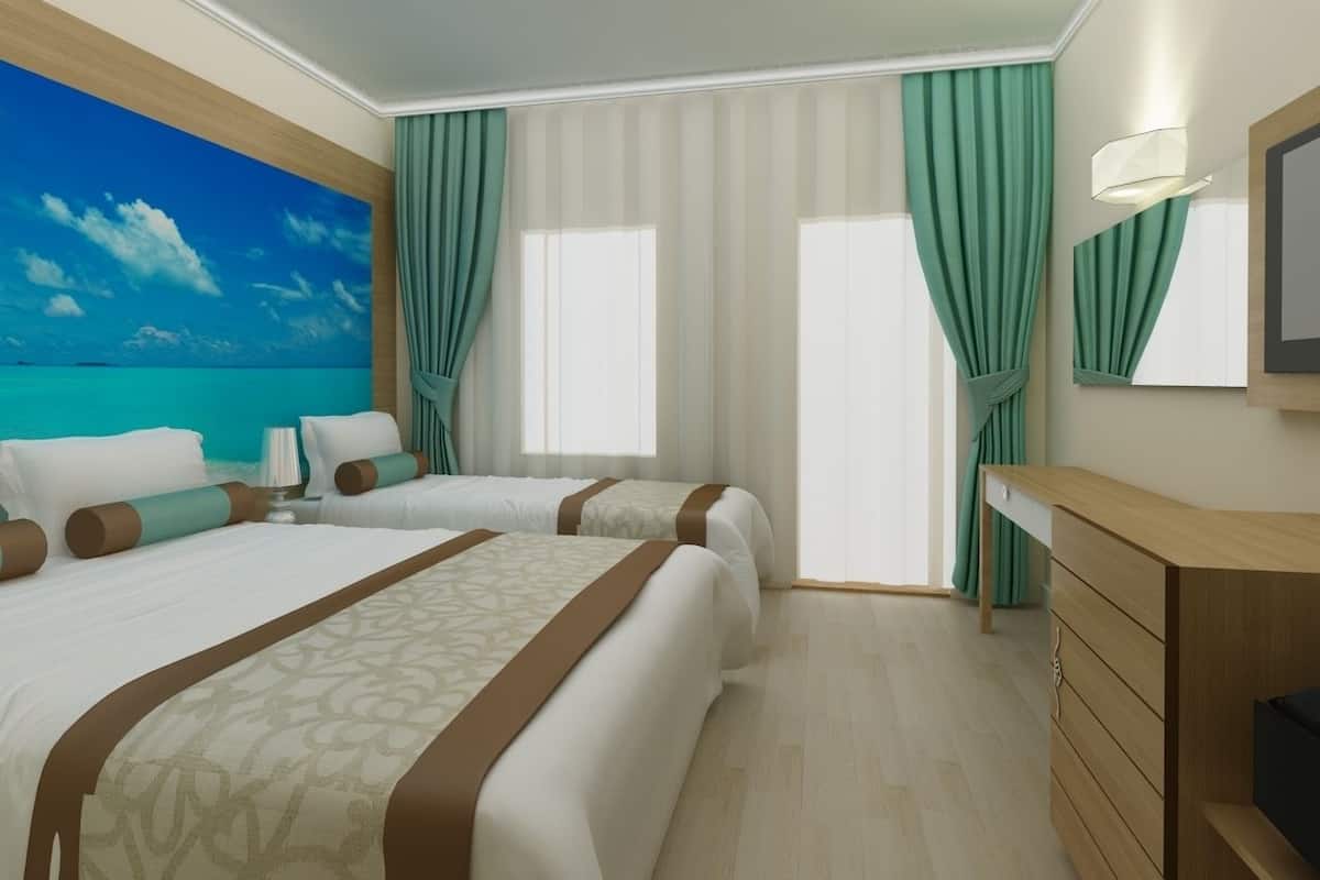 A hotel room with two beds, a large window with curtains, a wooden dresser, and a painting of a beach scene on the wall.