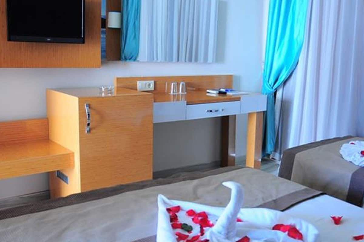 A hotel room with a bed, a desk, a television, and a bathroom.