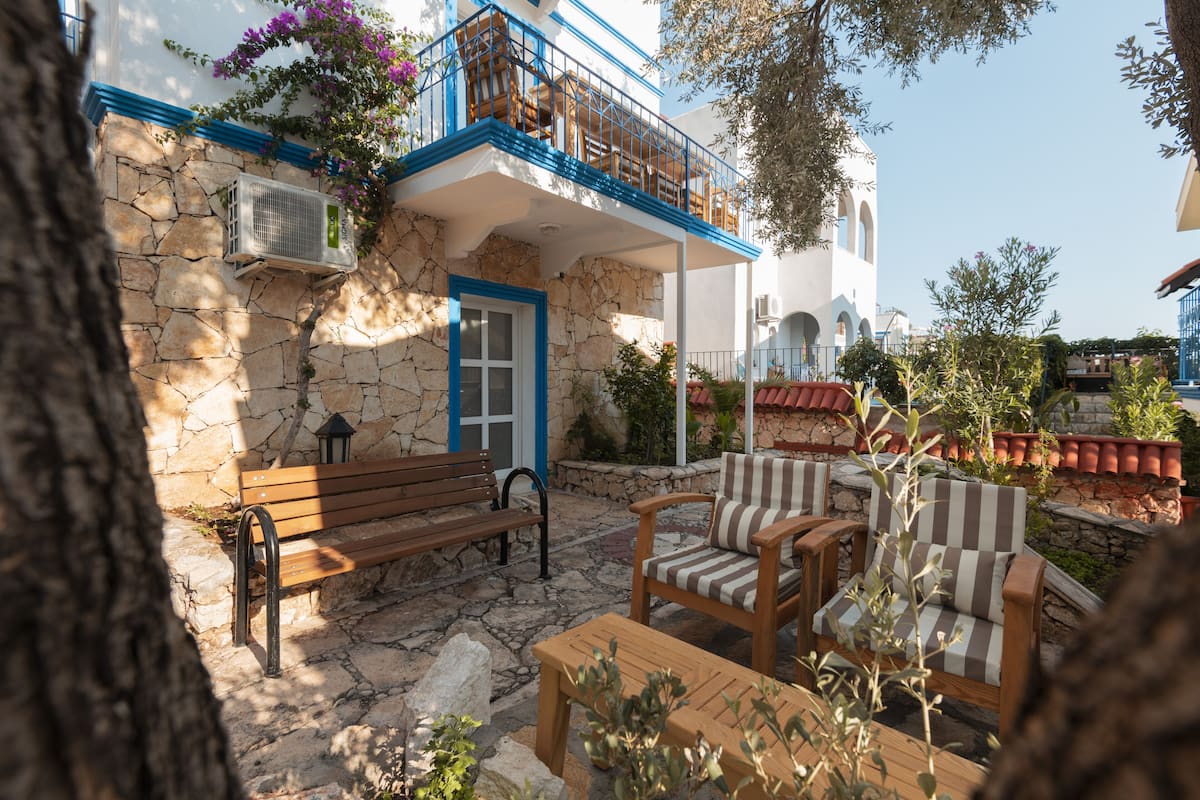 Un bâtiment en pierre doté d’un balcon, d’un banc et de deux chaises à rayures.