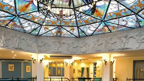 A spacious lobby with a grand staircase, a fountain, and a stained glass ceiling. - Soothe Hotel (Kas)