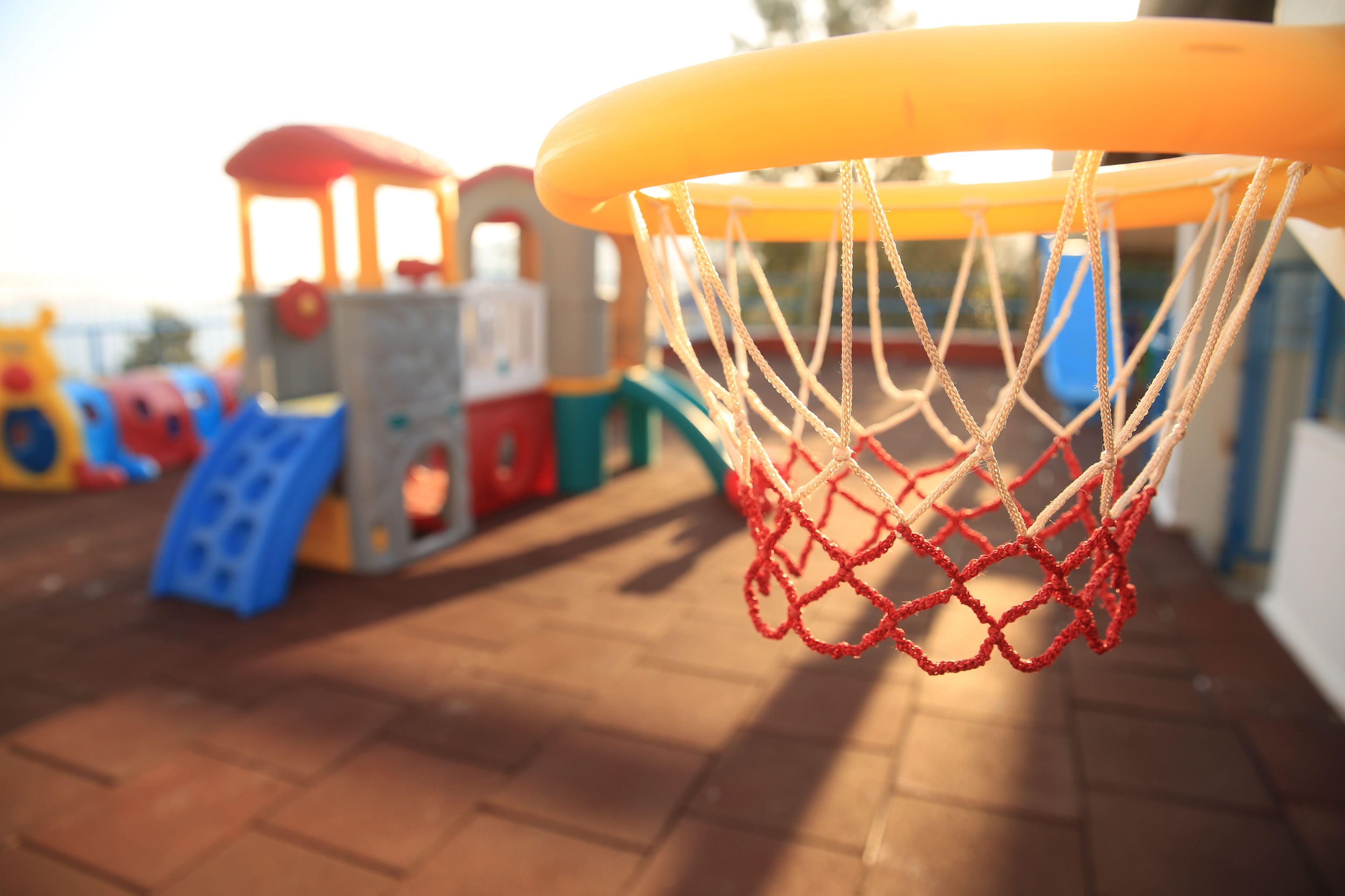 A close-up of a basketball hoop with a net, part of a playground structure.