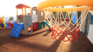 A close-up of a basketball hoop with a net, part of a playground structure.