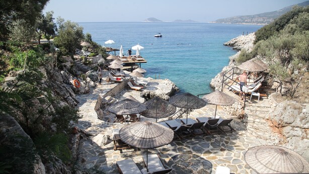 A coastal terrace with stone flooring, sun loungers, and umbrellas, overlooking the sea. - Soothe Hotel (Kas)