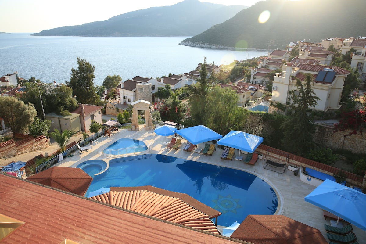 Un complexe hôtelier doté d’une piscine, de chaises longues et offrant une vue sur la mer.