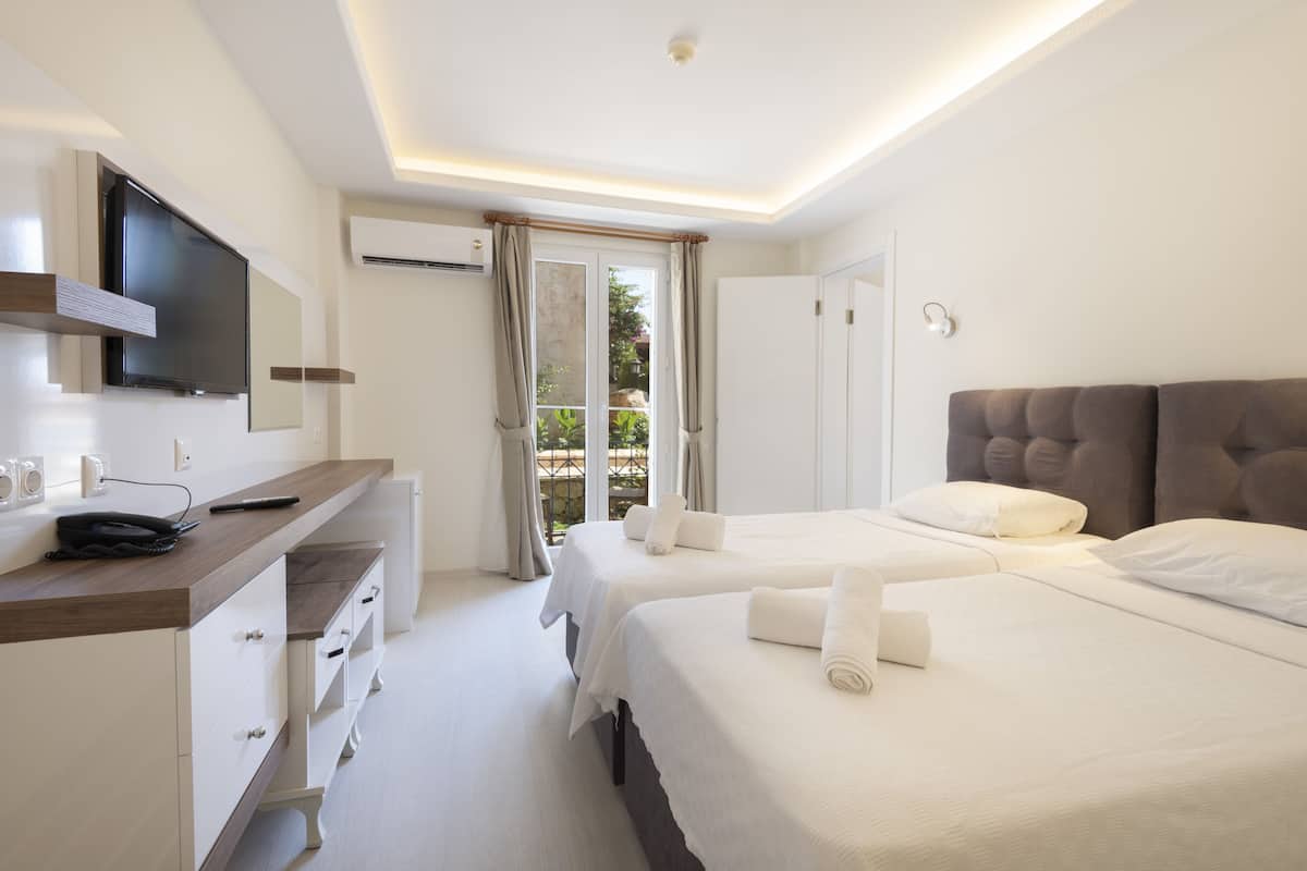 Une chambre d’hôtel avec deux lits, une télévision, un bureau et une fenêtre avec des rideaux.