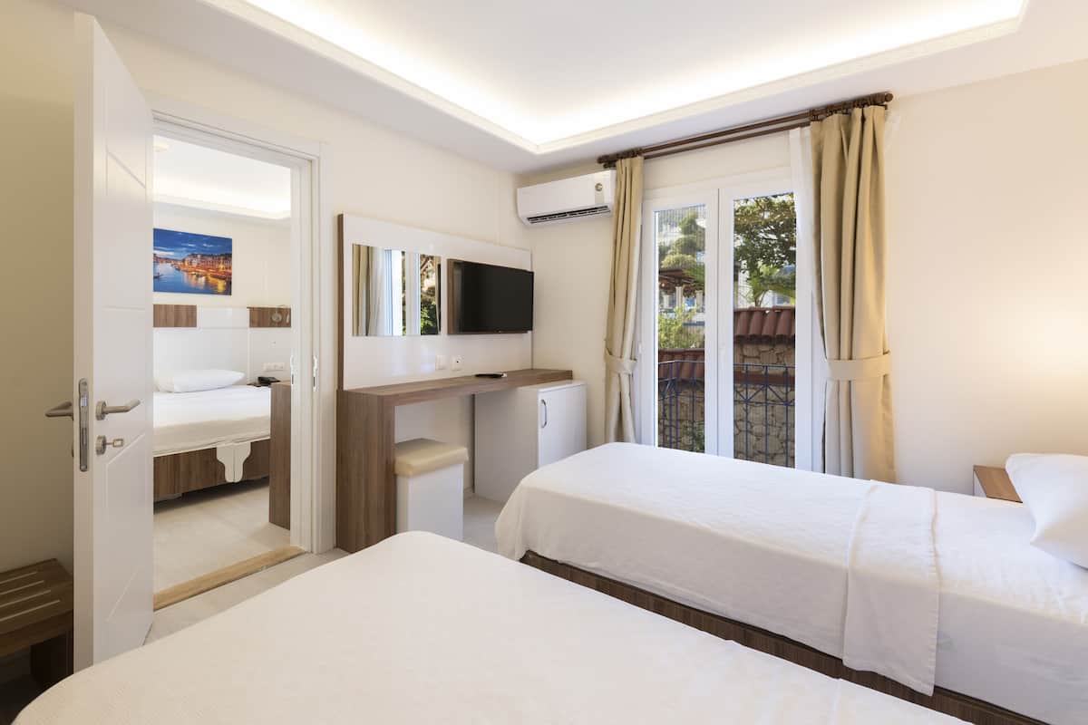 Une chambre d’hôtel avec deux lits, une télévision, un bureau et une petite kitchenette.