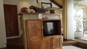 A wooden entertainment unit with a television, decorative vases, and a small table with items on top. - Red Garden Resort (Hengchun)