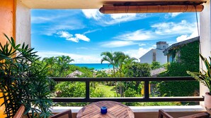 A wooden table and chairs on a balcony with a view of the ocean and greenery. - Red Garden Resort (Hengchun)