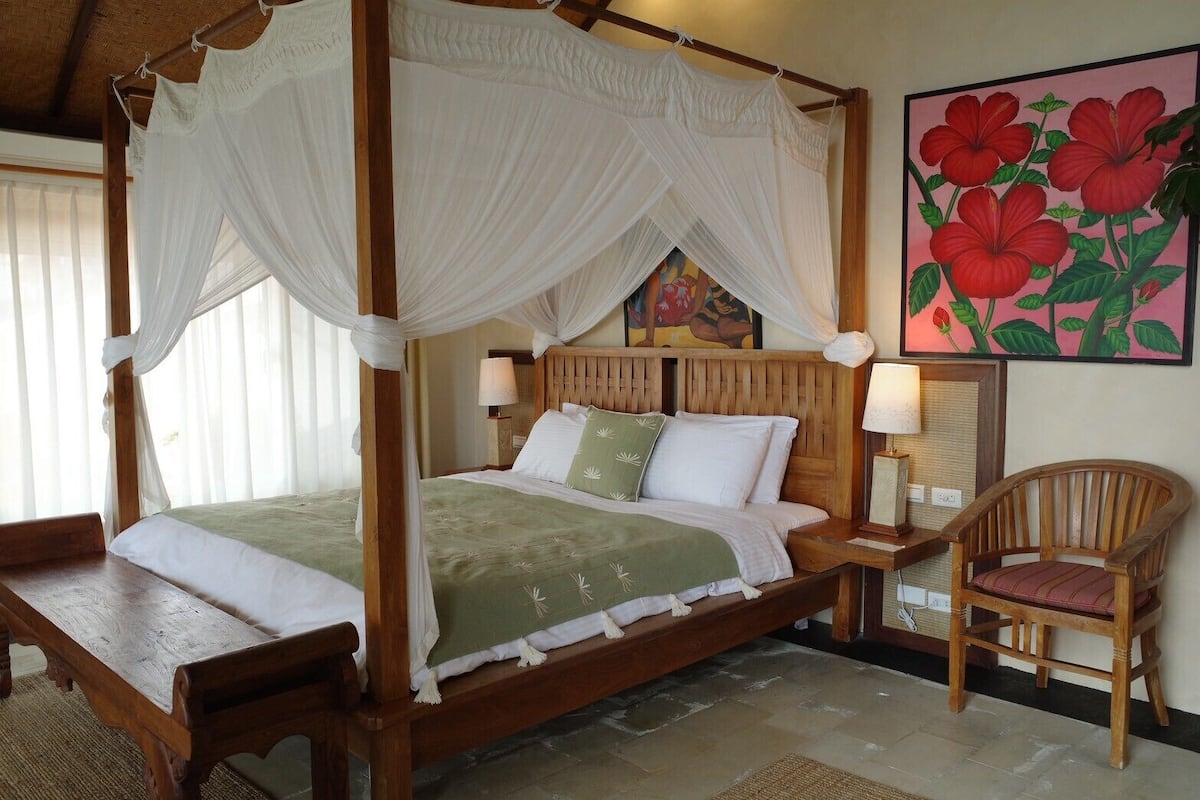 A four-poster bed with a canopy, wooden headboard, and bedside lamps.