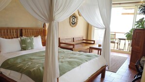 A bed with a canopy, a wooden headboard, and a green bedspread. There is a wooden bench and a plant in the corner. - Red Garden Resort (Hengchun)