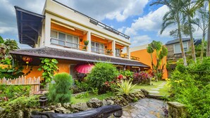 A two-story house with a balcony, surrounded by lush greenery and a stone pathway. - Red Garden Resort (Hengchun)