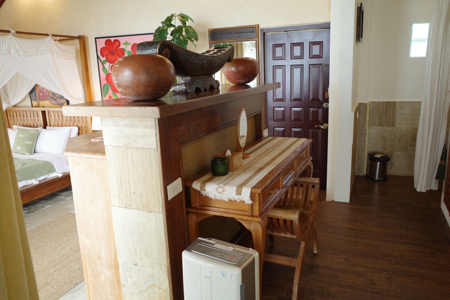 A cozy room with a bed, a wooden desk, a radiator, and a door with a geometric pattern.