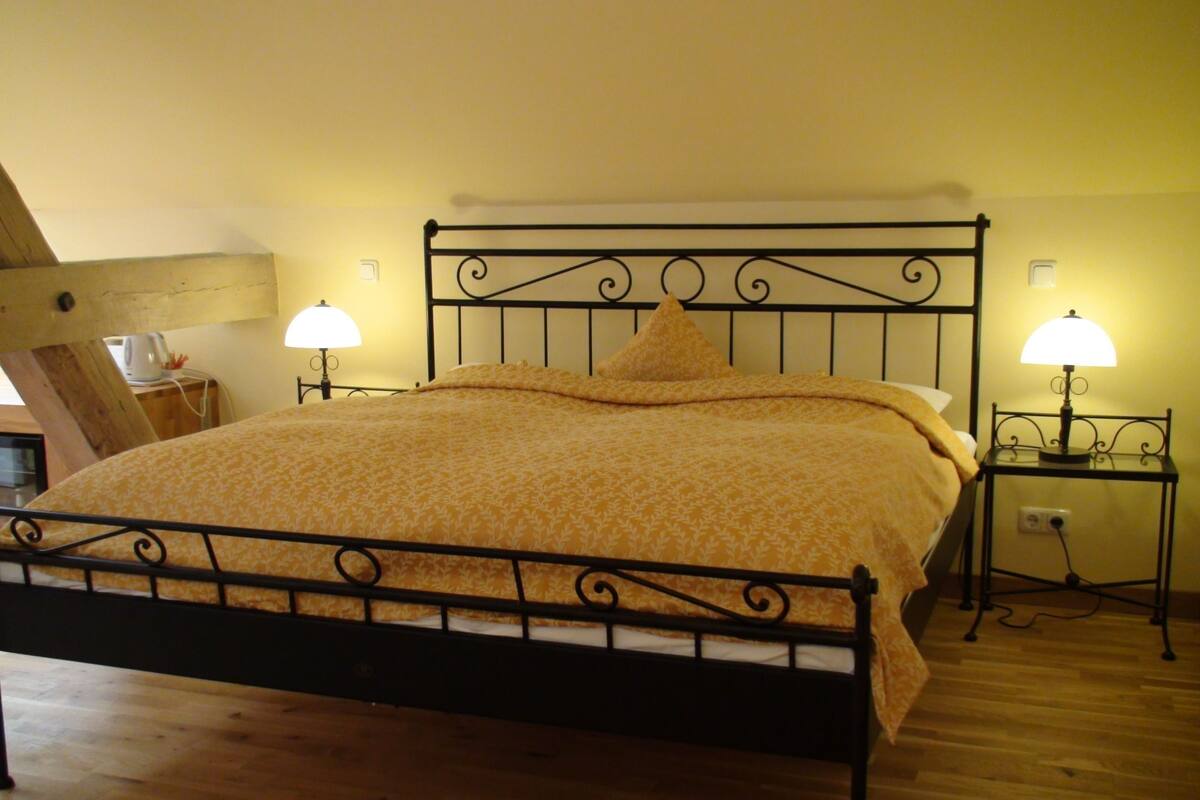 A bed with a metal frame, two bedside lamps, and a wooden floor.