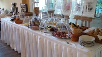 A buffet table with various food items and a coffee station.