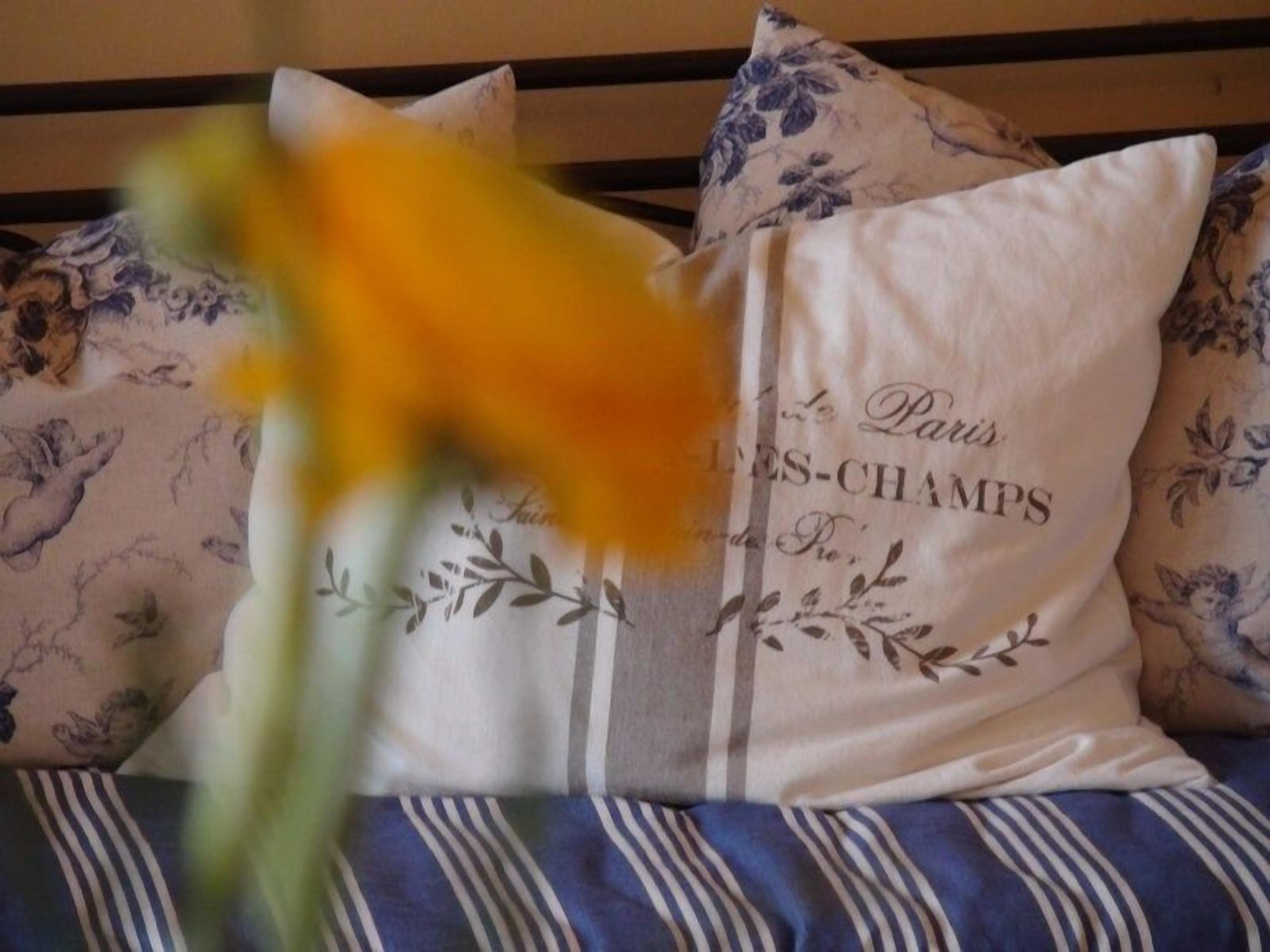 A bed with floral patterned pillows and a white pillow with text.