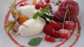 Une assiette de dessert avec divers fruits et une boule de glace.