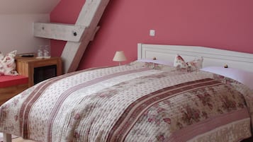 A bedroom with a wooden ceiling, a bed with a floral bedspread, a nightstand, and a lamp.