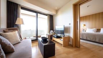 Una habitación de hotel moderna con sofá, televisión, una mesita y una cama.