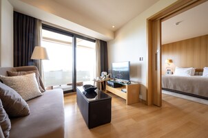 Una habitación de hotel moderna con sofá, televisión, una mesita y una cama.