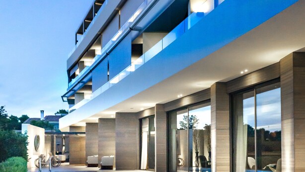 Een modern hotel met een zwembad, terras en een meerlaags gebouw.