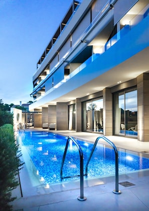 A modern hotel with a swimming pool, outdoor seating, and a multi-story structure. - Somewhere Boutique Hotel Vouliagmeni (Vari-Voula-Vouliagmeni)