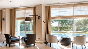 Een moderne woonkamer met een groot raam, uitzicht op een zwembad en een lamp.