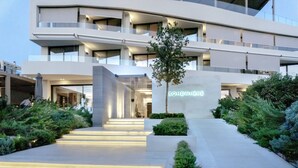 Een moderne hotelentree met een goed verlicht pad naar de deur, omringd door groen en een helder zicht op de architectuur van het gebouw.