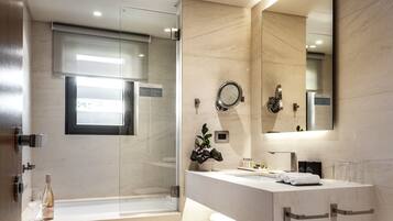 A modern bathroom with a glass shower enclosure, a large mirror, and a vanity with a sink and towel rack.