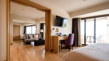 A hotel room with a bed, a desk, a chair, a sofa, and a TV.