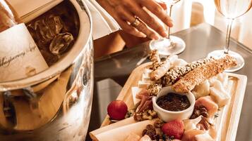 A charcuterie board with various meats, cheeses, and fruits, accompanied by a bottle of wine and glasses.