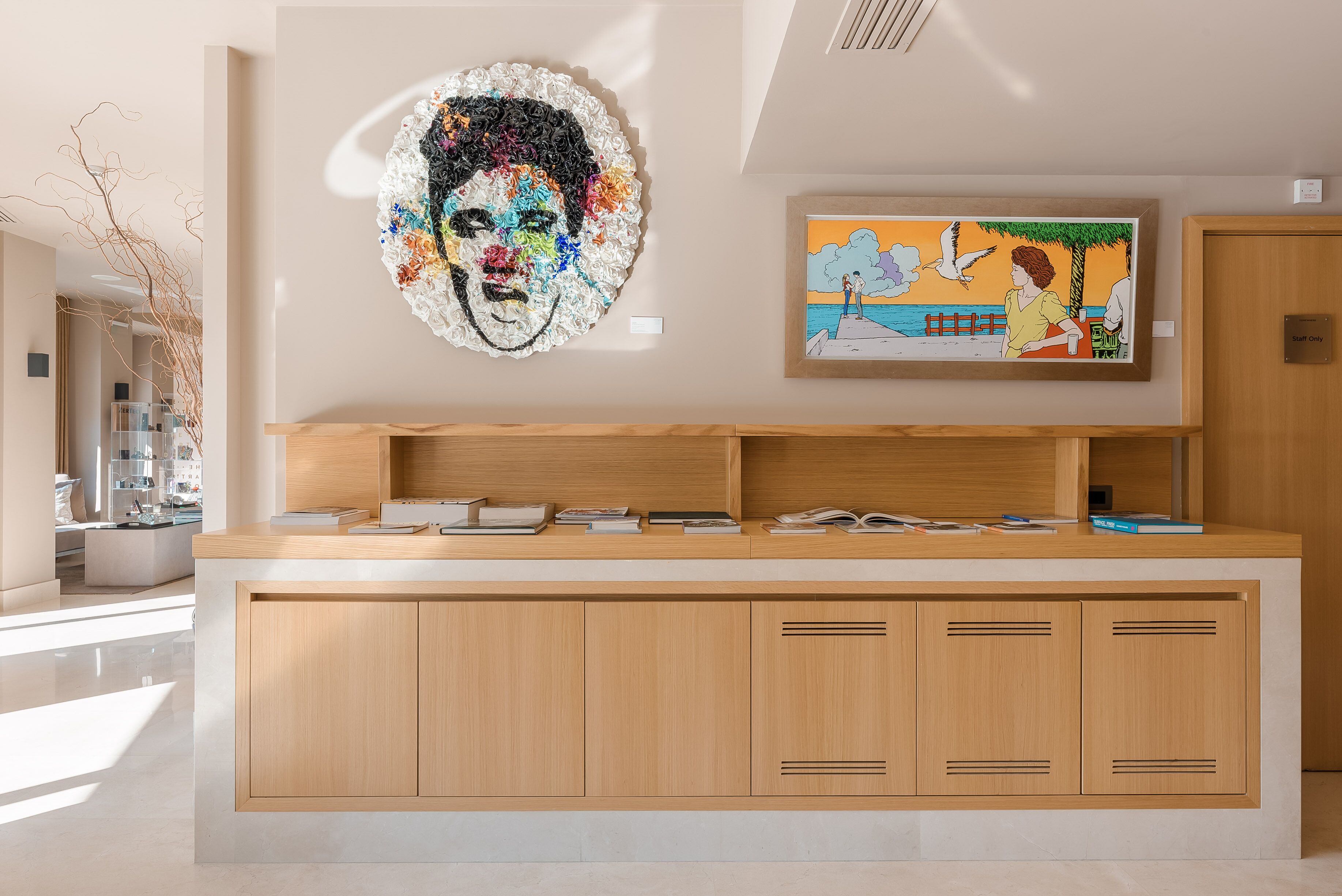 A reception desk with a wooden finish, a large abstract painting, and a framed artwork above it.
