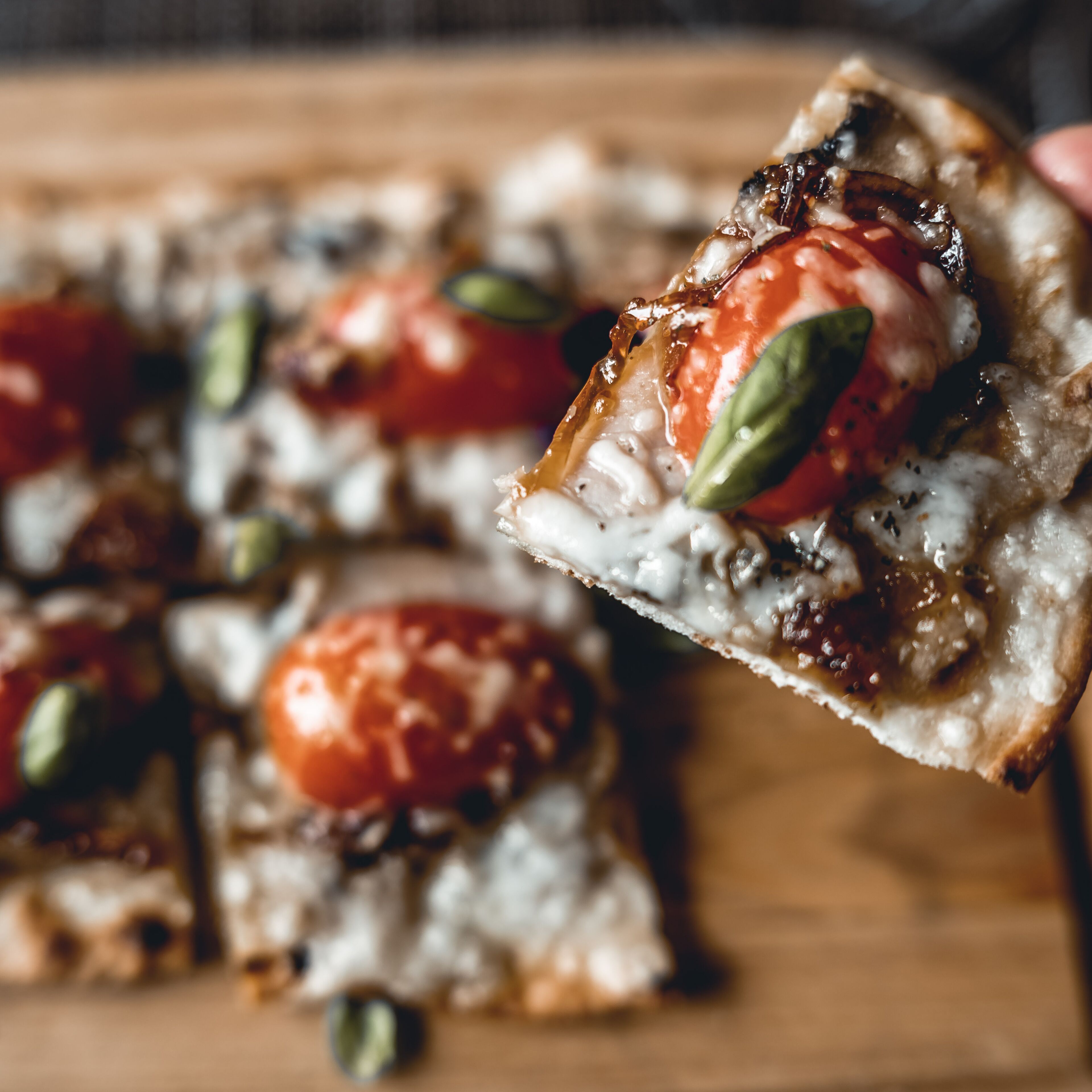 A close-up of a pizza with tomatoes and basil on a wooden board.