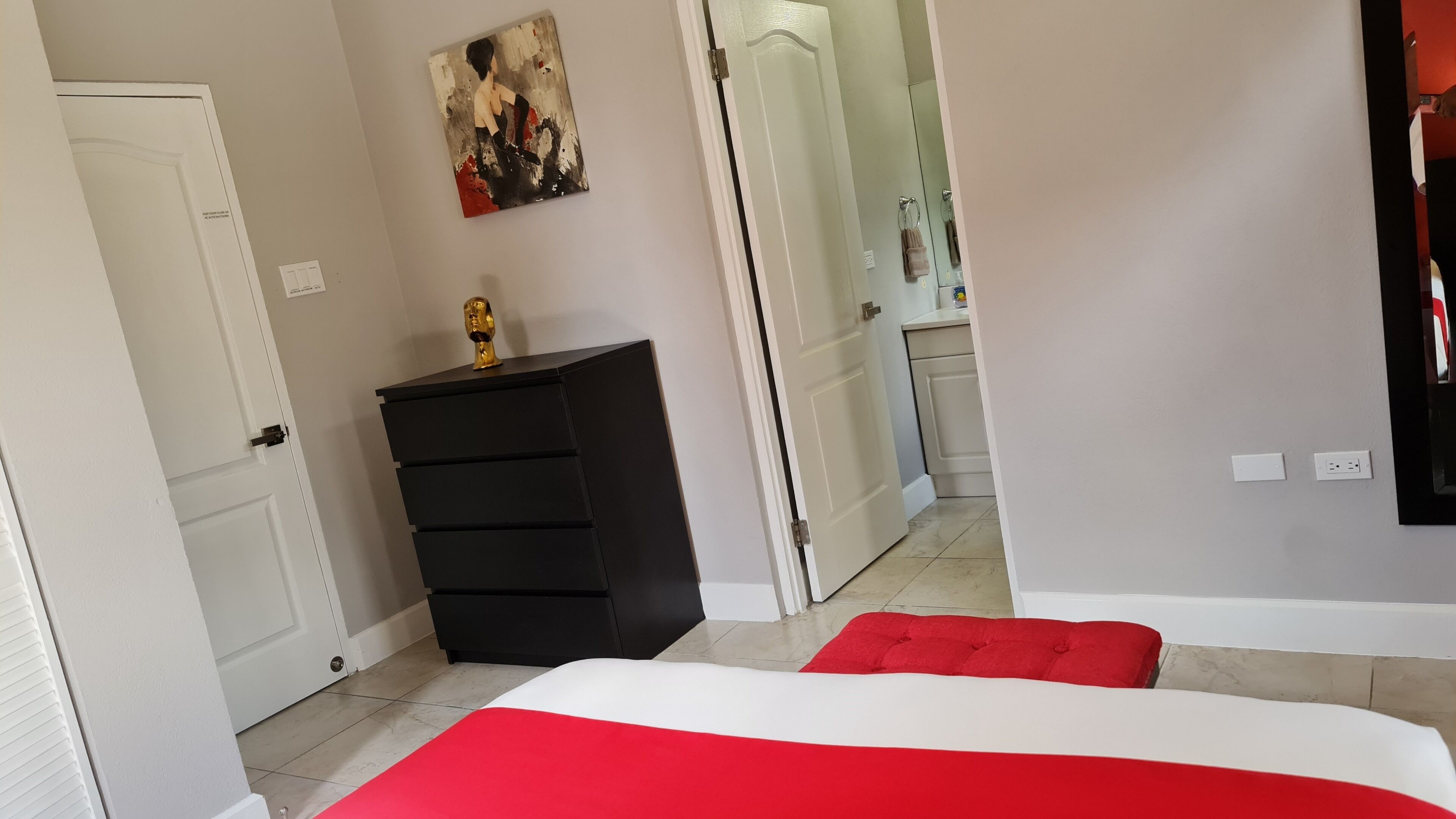 A bedroom with a bed, a dresser, a mirror, and a painting on the wall.
