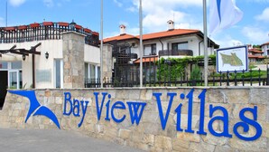 Un muro de piedra con el texto "Bay View Villas" y un logotipo azul.