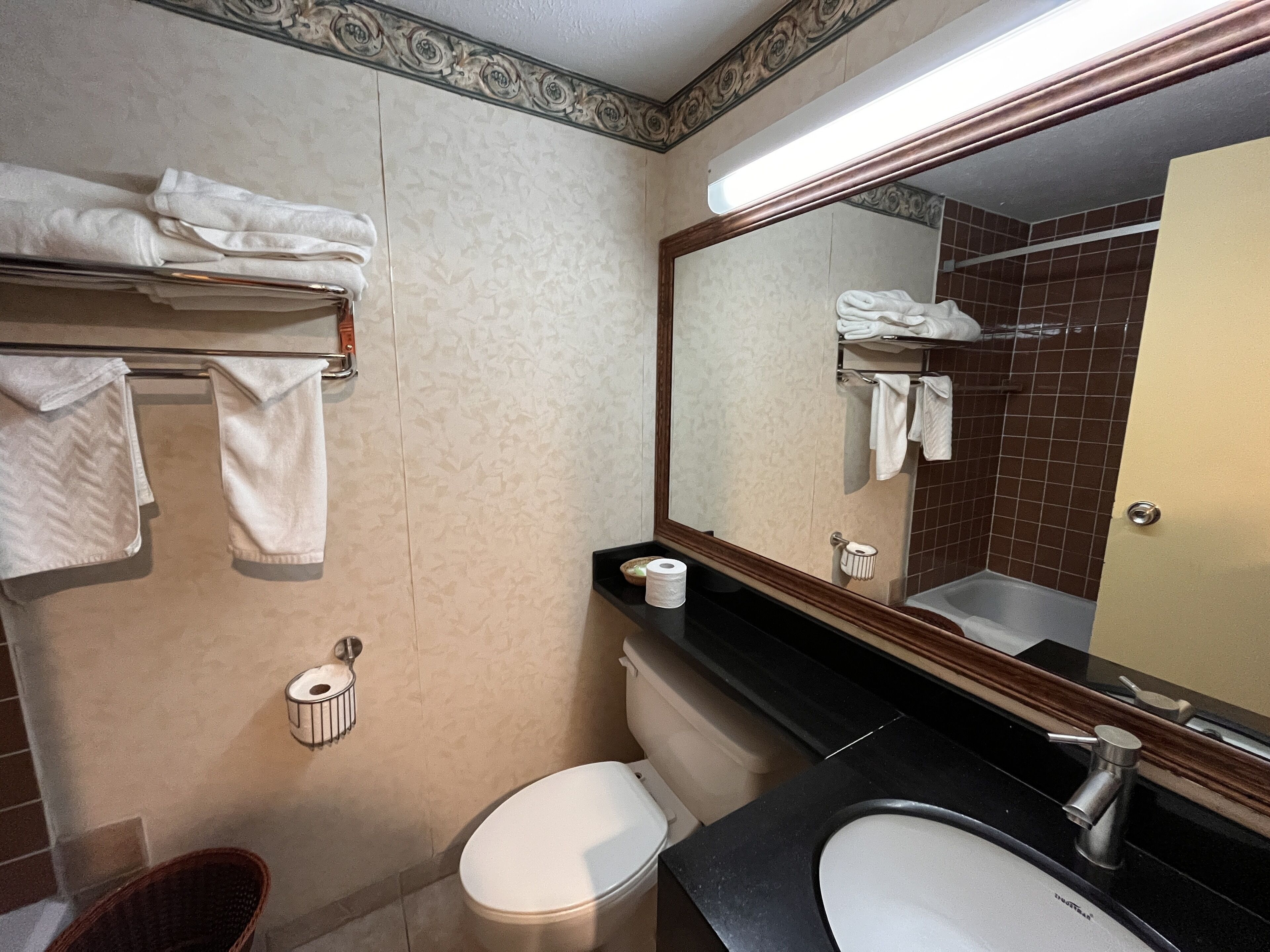 A bathroom with a toilet, sink, and a towel rack with folded towels.