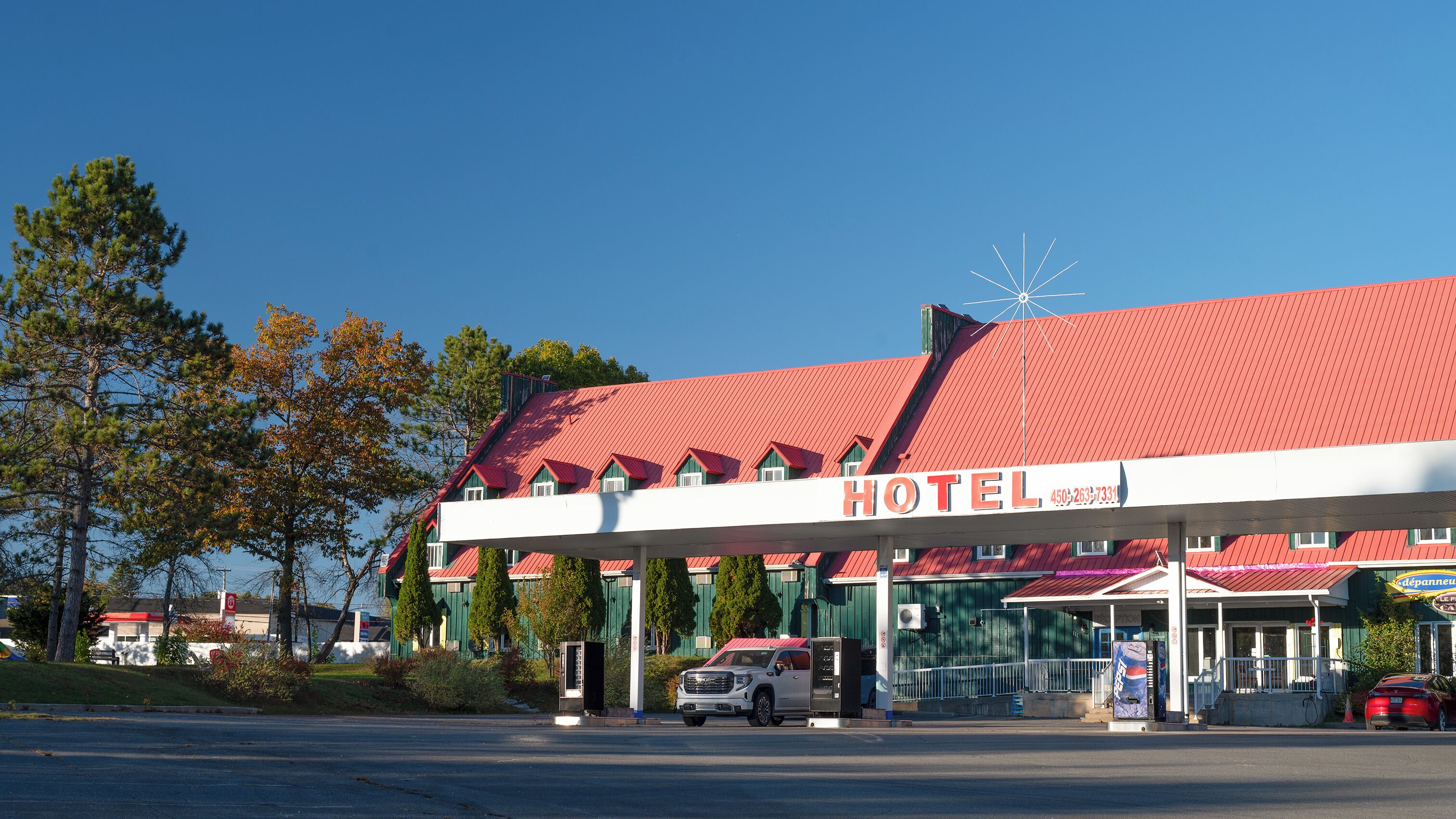 A hotel with a red roof and a gas station in front.
