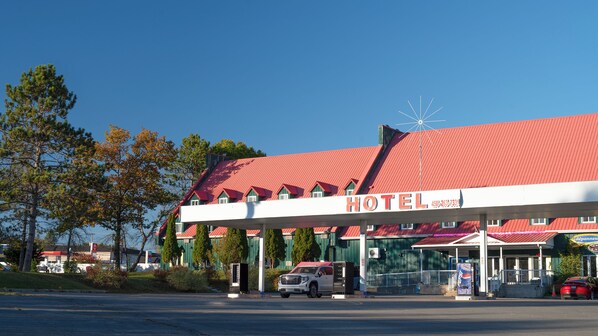 A hotel with a red roof and a gas station in front.