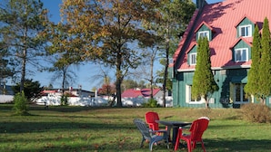A house with a red roof, green walls, and a lawn with two red chairs and a table. - Hotel Cowansville (Cowansville)