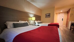 A hotel room with two beds, a wooden headboard, a desk, and a lamp. - Hotel Cowansville (Cowansville)