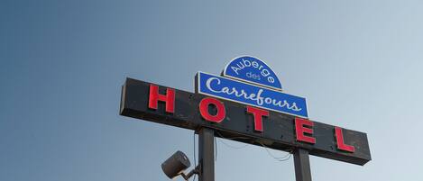 A hotel sign with 'Auberge des Carrefours' and 'HOTEL' written on it.