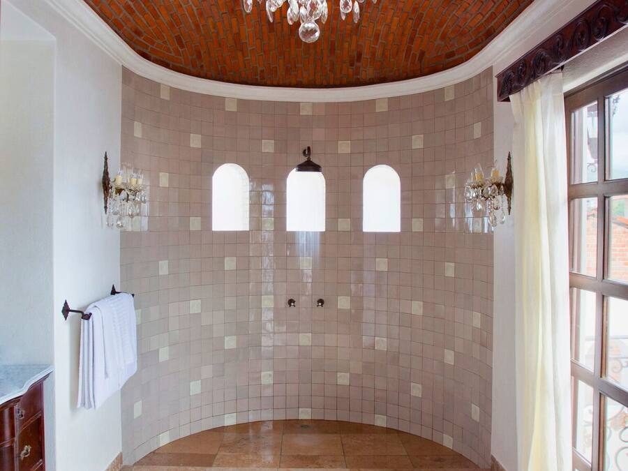 A spacious bathroom with a curved floor, a brick ceiling, and a large chandelier.