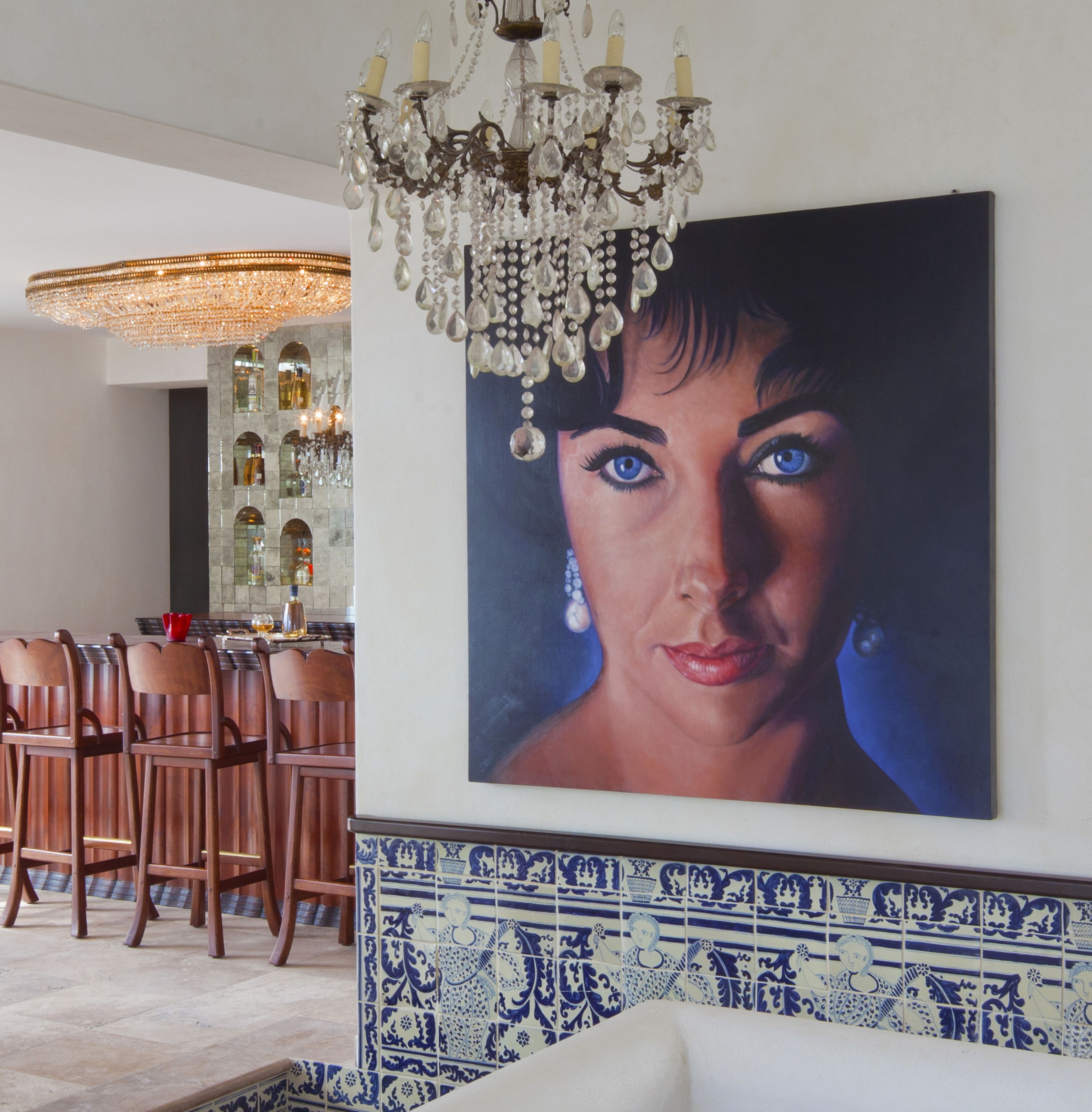 A dining area with a chandelier, wooden chairs, and a tiled backsplash.