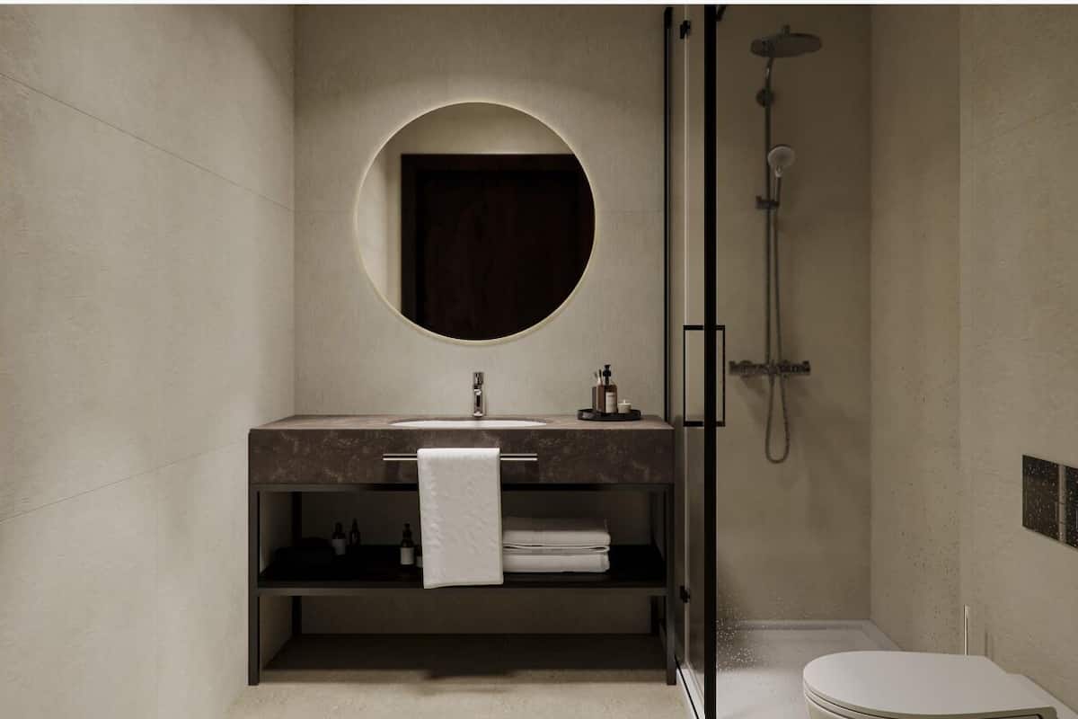 A modern bathroom with a round mirror, a sink, a shower, and a toilet.