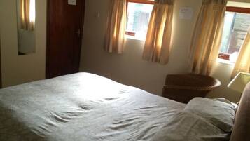 Une chambre à coucher avec un lit, une chaise, une fenêtre avec des rideaux et une porte.
